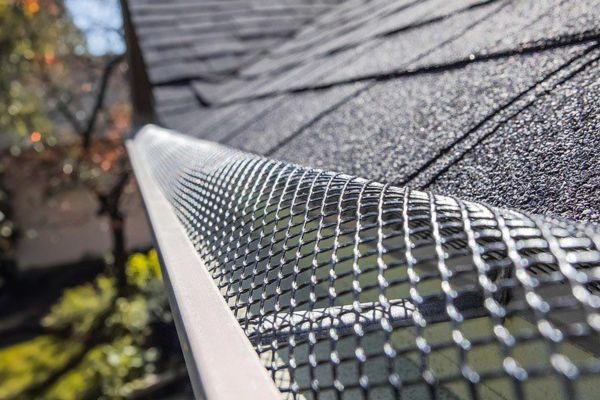 Professional installer fitting gutter guards for enhanced gutter protection on a residential home.