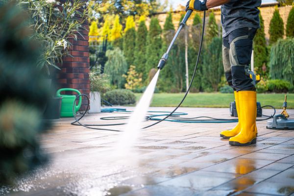 Professional cleaner using a power washer to clean an outdoor patio in New Jersey.